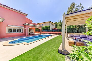 A pink house with a large swimming pool in front of it
