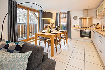 A kitchen with a table and chairs and a clock on the wall