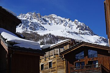 A snowy mountain is behind a row of wooden buildings