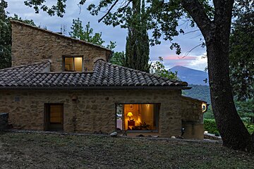 A stone house with a tiled roof is lit up at night
