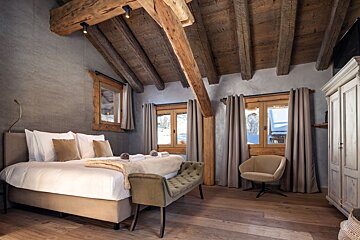 A bedroom with a large bed and a chair