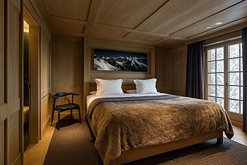 A bedroom with a large picture of mountains above the bed