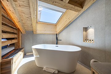 A bathtub in a bathroom with a skylight above it