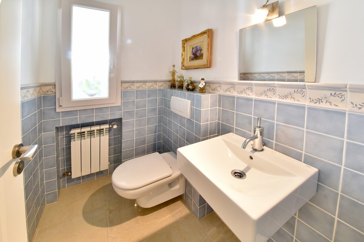 A bathroom with blue tiles and a toilet and sink