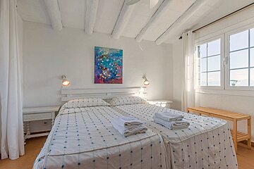 A bedroom with two beds and a painting on the wall