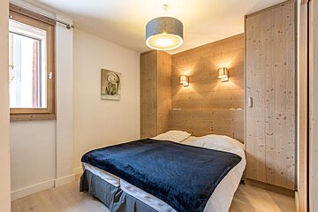 A bedroom with a bed a desk and a window
