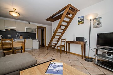 A living room with a wooden staircase and a book titled altis