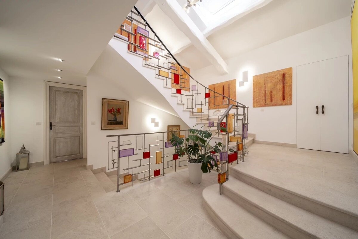 Modern interior featuring stone floors and a staircase with an artistic railing adorned with colorful glass panels.