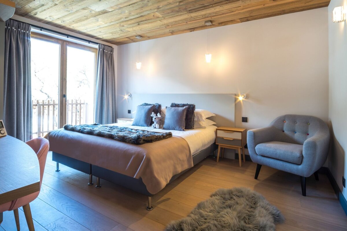 A bedroom with a large bed and a chair