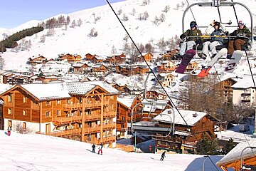 People on a ski lift with a snowboard that says lotto on it