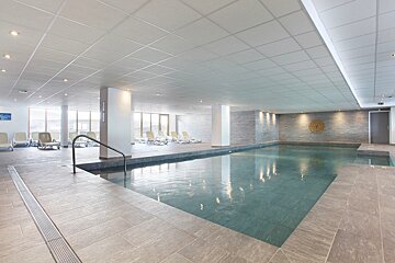 A large indoor swimming pool with chairs around it
