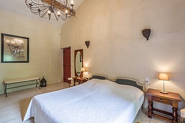 A bedroom with a large bed and a chandelier
