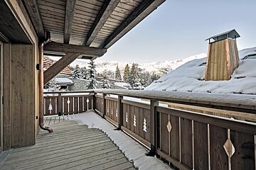 A balcony with snow on the ground and trees on the railing