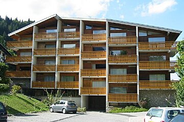 A building with a lot of balconies and cars parked in front of it
