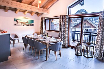 A dining room with a table and chairs and a balcony