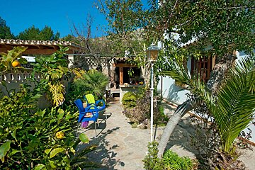 A blue chair with a yellow blanket on it sits in front of a house