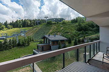 A balcony with a view of a ski lift and a house