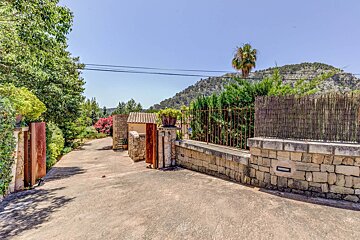A stone wall with a wooden gate leading to a house