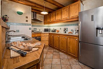 A kitchen with wooden cabinets and a stainless steel refrigerator