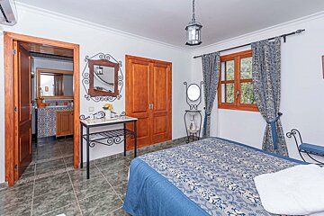 A bedroom with a blue bed and a mirror on the wall