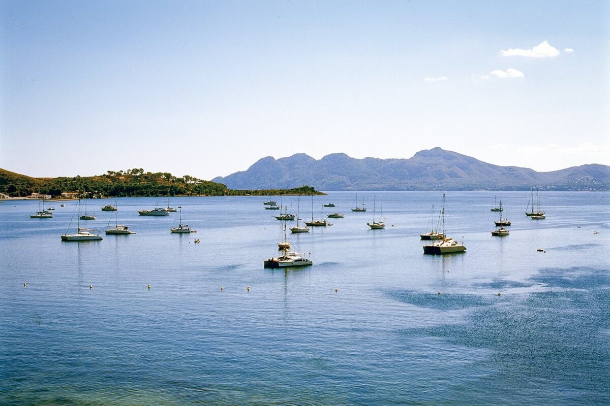 A large body of water filled with boats and mountains in the background