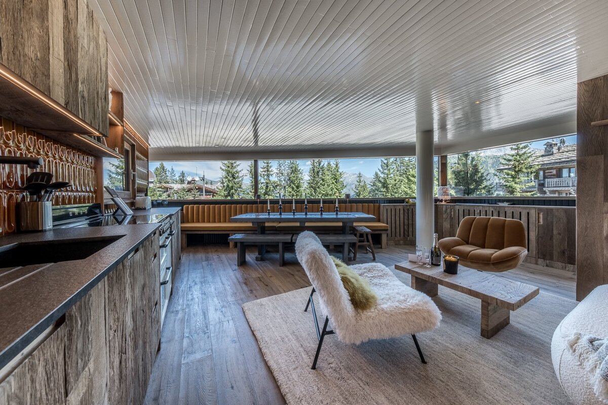 A modern open-plan living space with a kitchen, dining area, lounge, and panoramic mountain views through large windows.