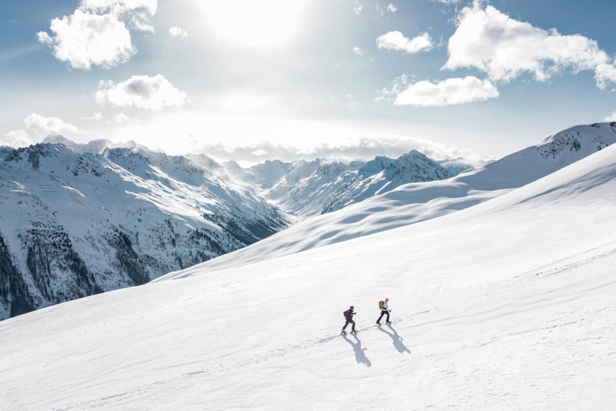 Two people skiing down a snow covered mountain