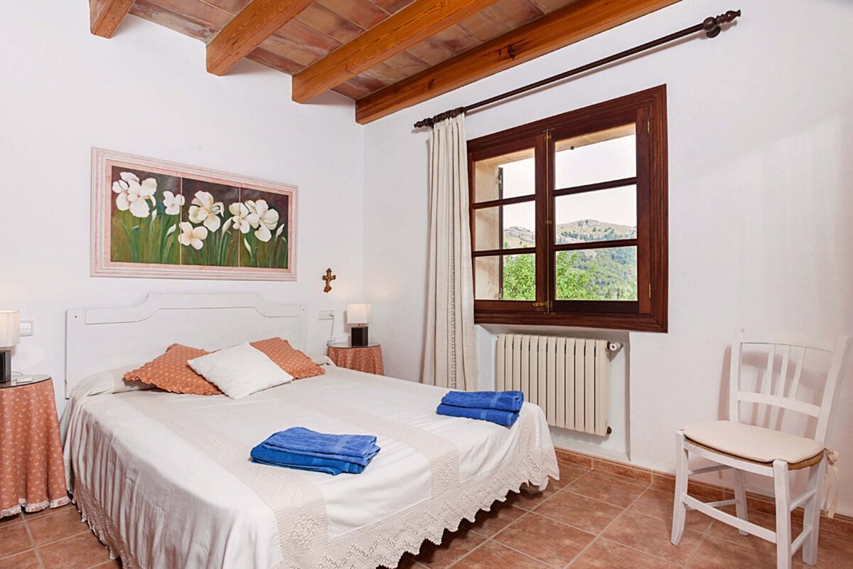 A bedroom with a painting on the wall above the bed