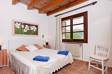 A bedroom with a painting on the wall above the bed