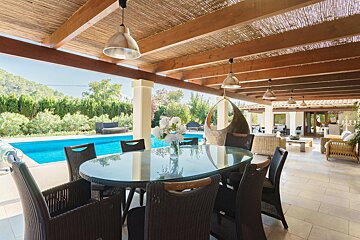 A patio with a table and chairs and a pool in the background