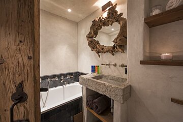 A bathroom with a stone sink and a wooden mirror