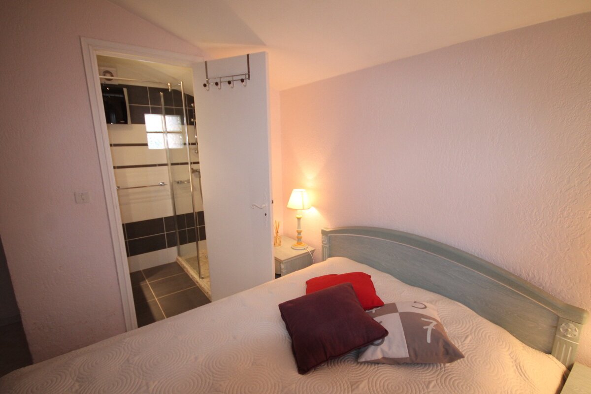 A bedroom with a bed a nightstand and a lamp
