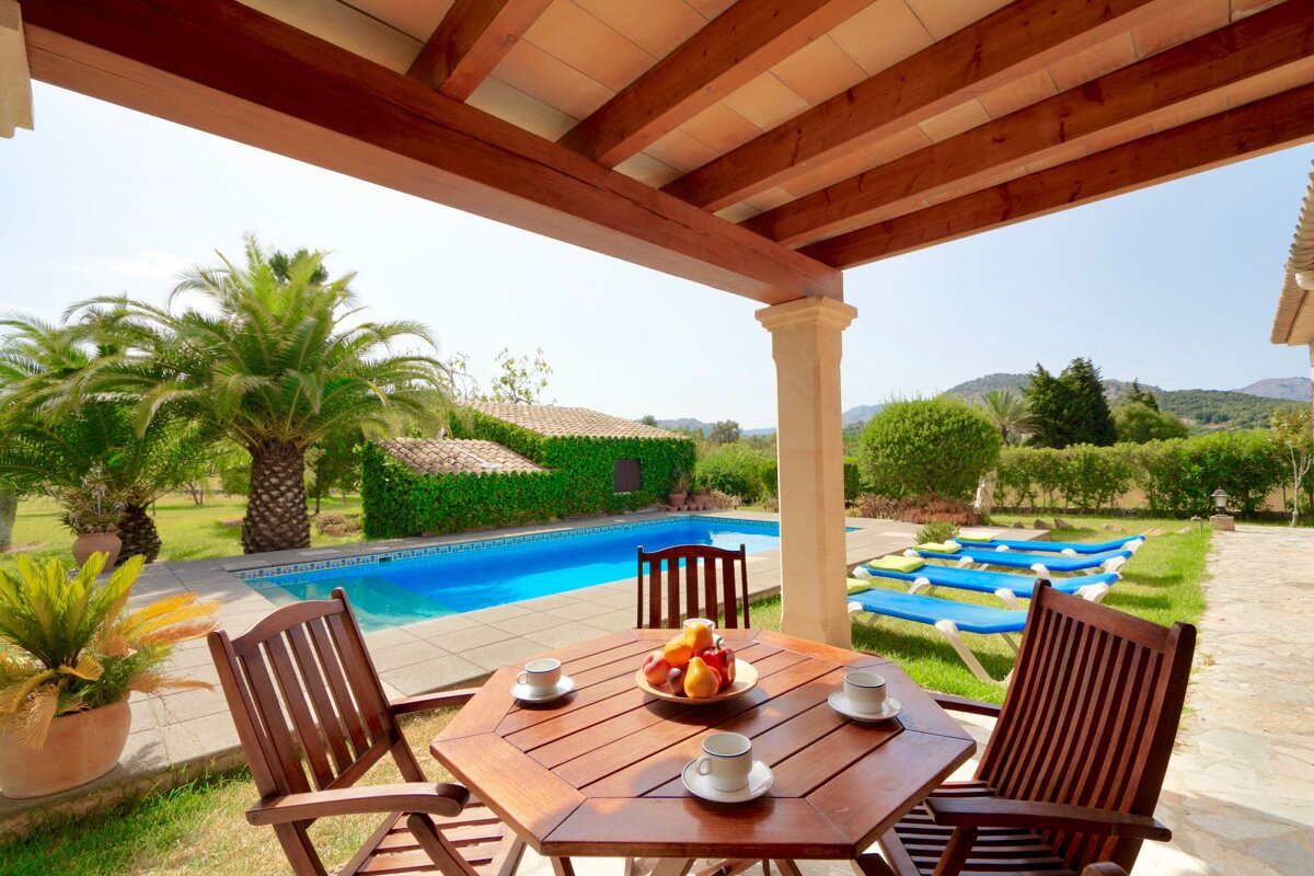 A table with a bowl of fruit on it sits in front of a pool