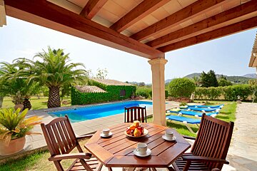 A table with a bowl of fruit on it sits in front of a pool