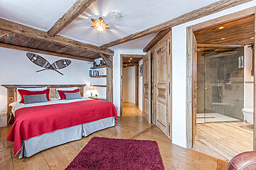 A bedroom with a red bed and snowshoes on the wall
