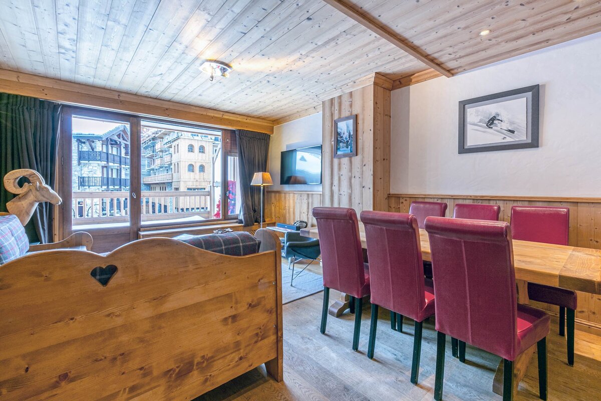 A living room with red chairs and a wooden table