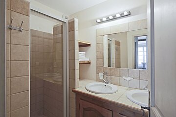 A bathroom with two sinks and a walk in shower
