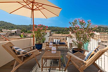 A balcony with chairs and a table under an umbrella