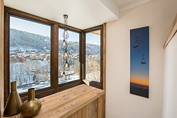 A picture of a ski lift hangs on a wall next to a window