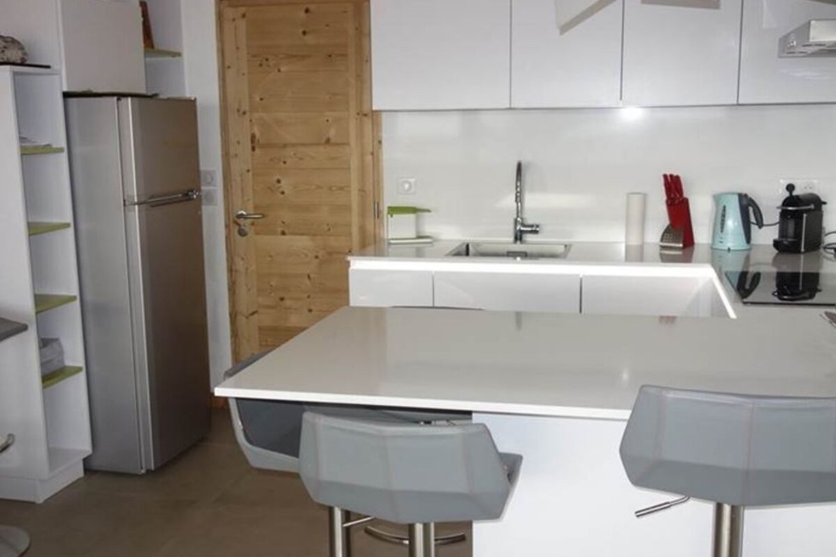 A kitchen with white cabinets and a stainless steel refrigerator