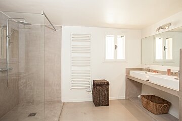 A bathroom with a walk in shower and two sinks