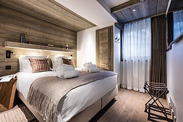 A bedroom with a large bed and a stool