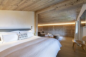 A bedroom with a wooden ceiling and a bed