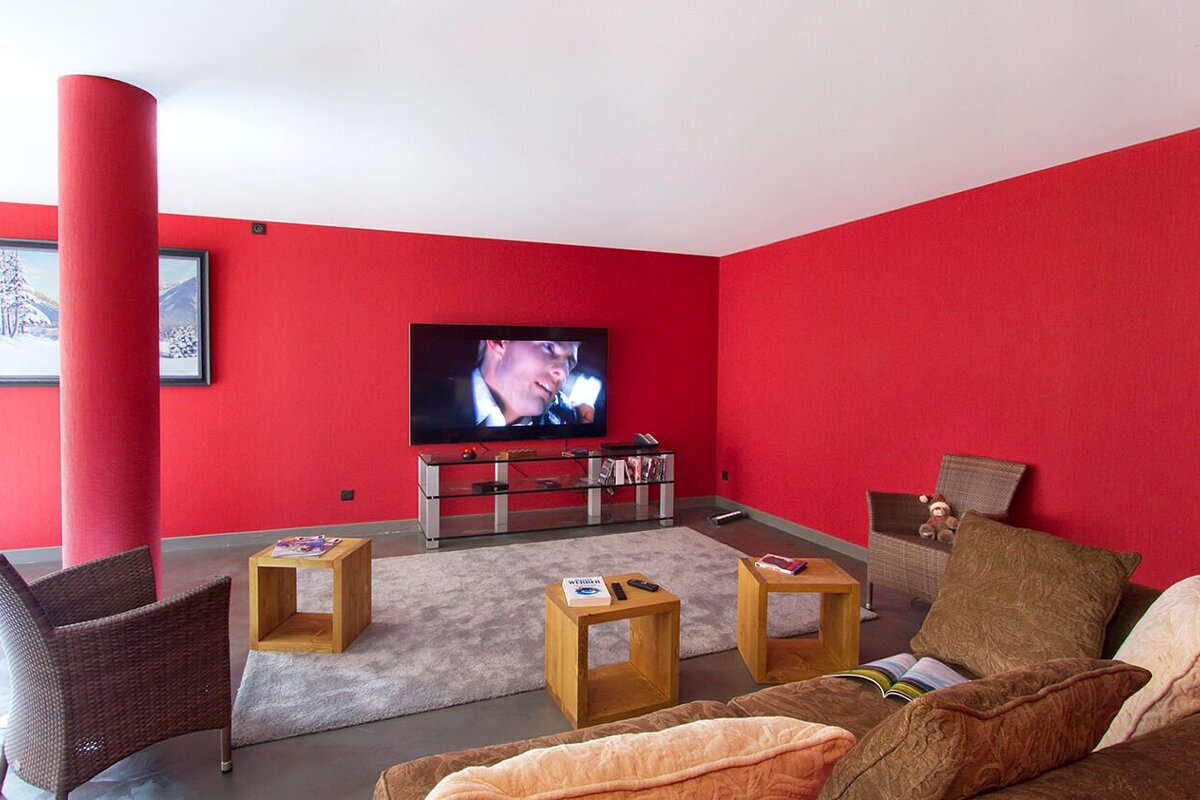 A living room with red walls and a flat screen tv