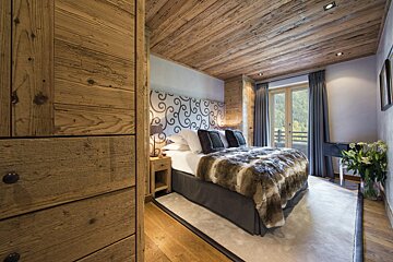 A bedroom with wooden walls and a bed with a fur blanket