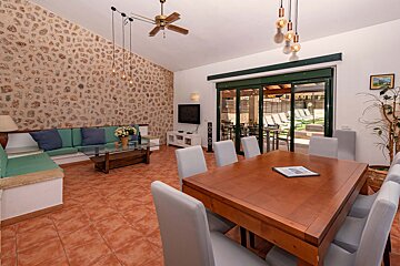 A living room with a table and chairs and a ceiling fan