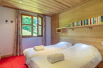 A bedroom with two beds and a shelf full of books