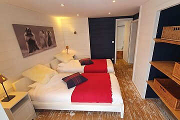 A bedroom with two beds and a painting on the wall