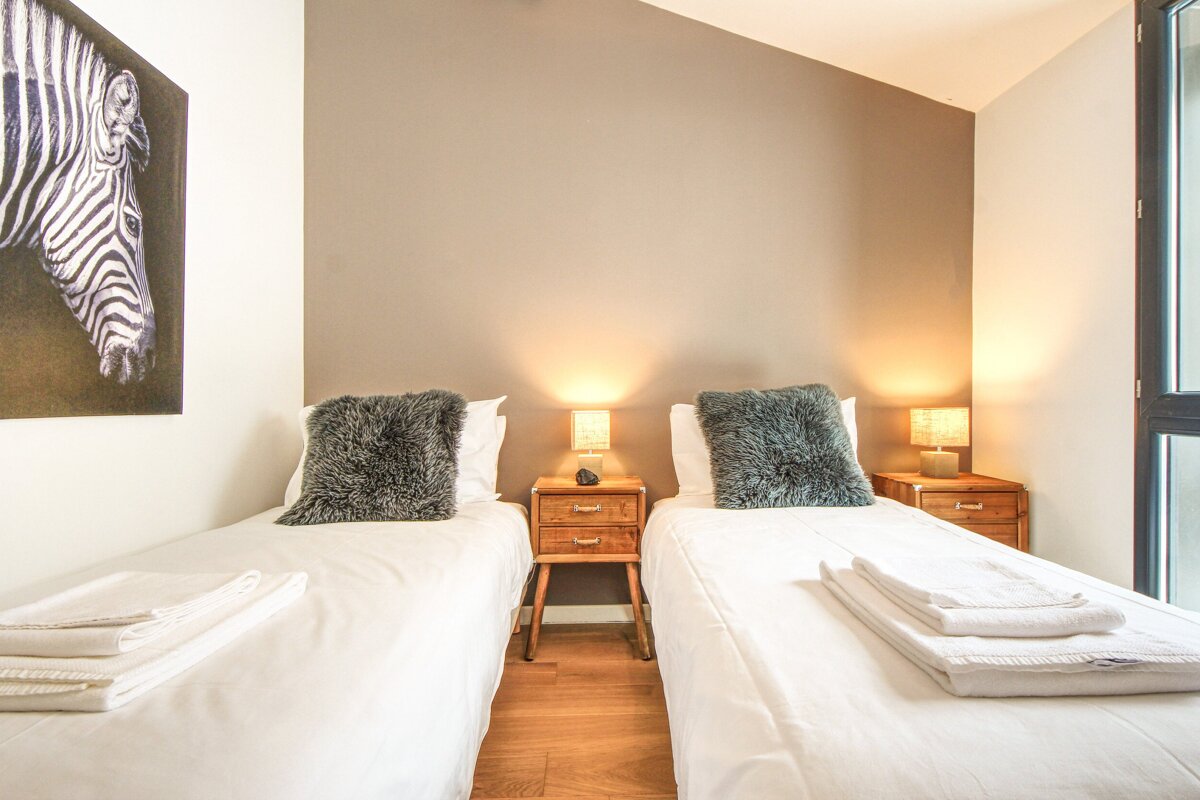 A bedroom with two beds and a picture of a zebra on the wall
