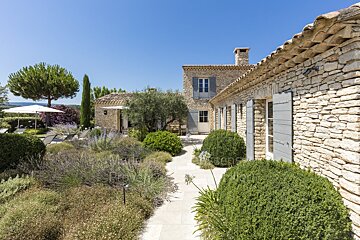 A stone house with blue shutters is for sale